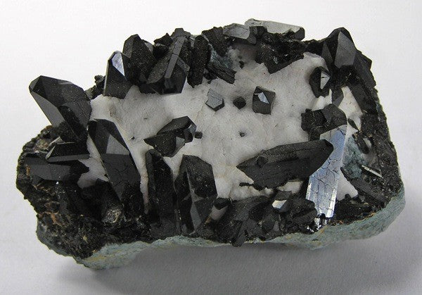 Natural neptunite crystals on natrolite from San Benito County, California; Rob Lavinsky, CC BY-SA 3.0 — Roosters Peacock crystal guide