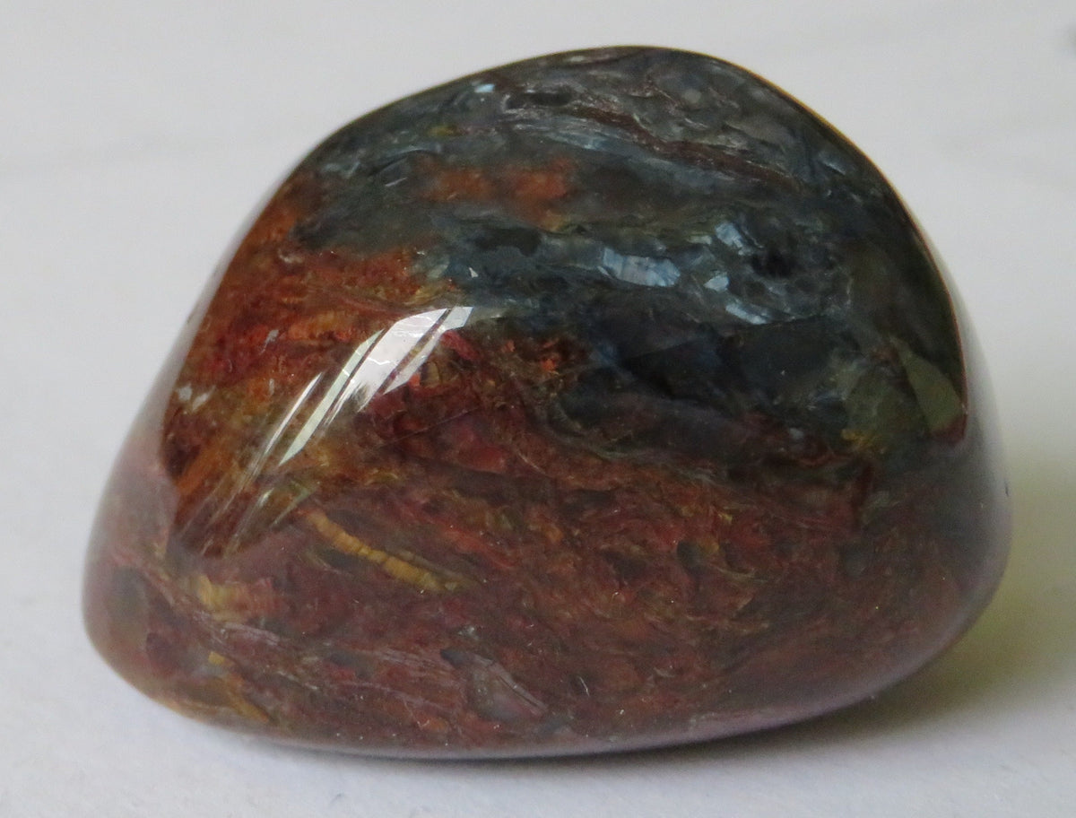 Polished natural Pietersite stone showing chatoyant blue, gold, and brown patterning; Maimaid, CC BY-SA 4.0 — Roosters Peacock crystal guide