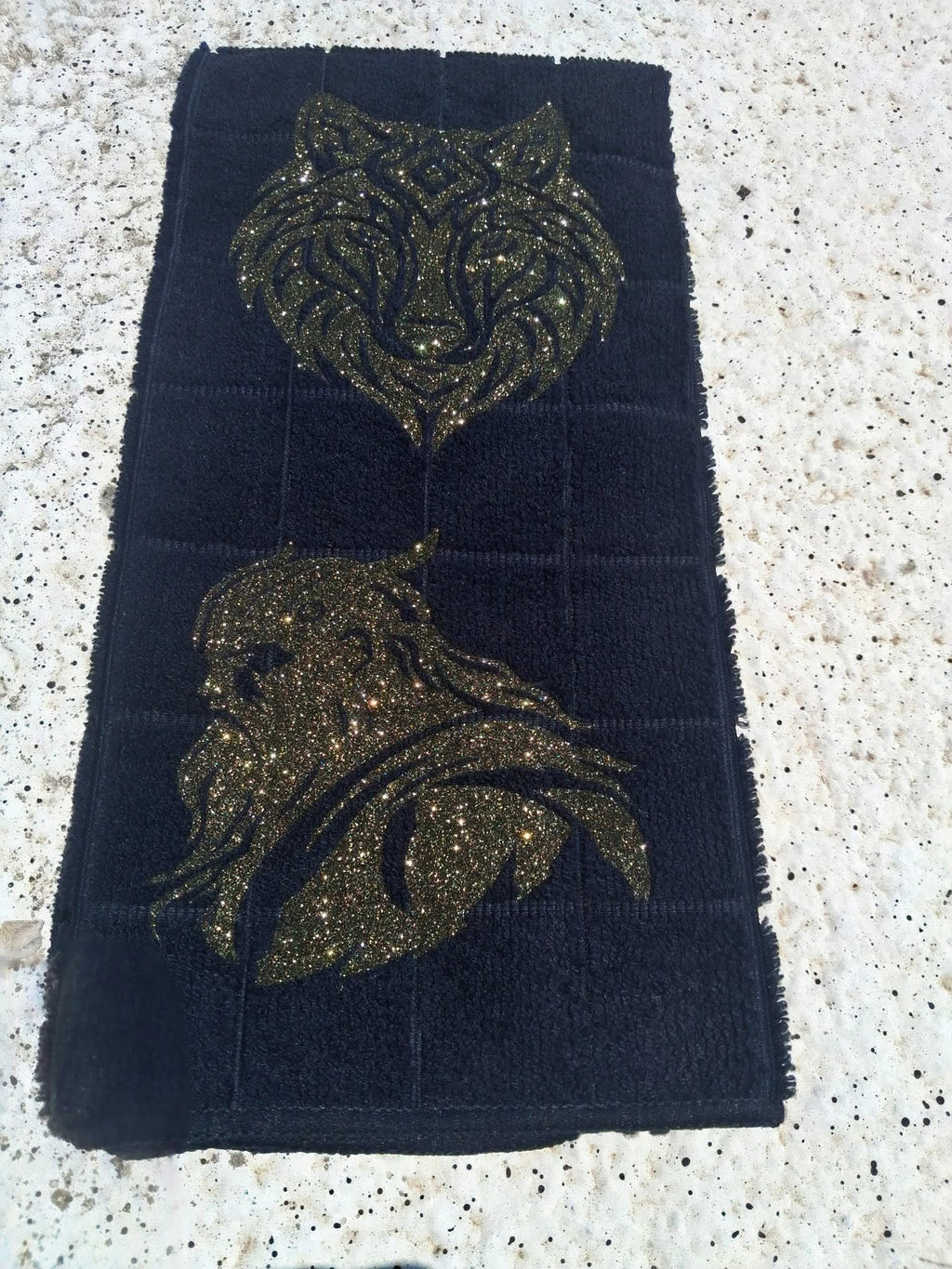 Black microfiber wolf and Viking warrior hand towel angled view on concrete showing full gold glitter design
