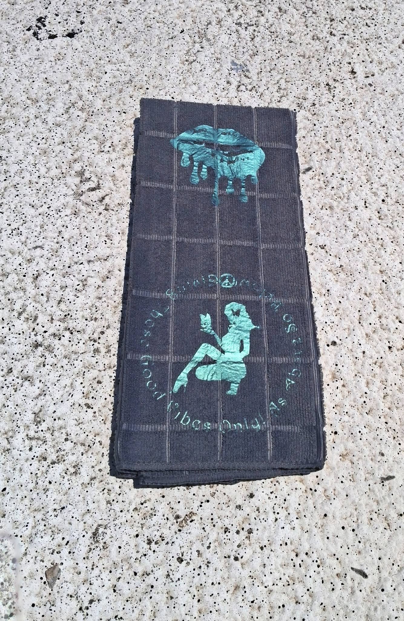 Black microfiber Good Vibes Only hand towel full view with hook showing dripping lips and woman silhouette teal design