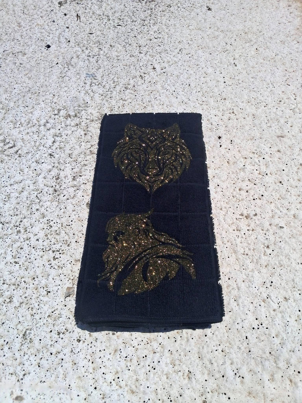 Black microfiber wolf Viking warrior hand towel close up showing gold glitter wolf face detail on concrete