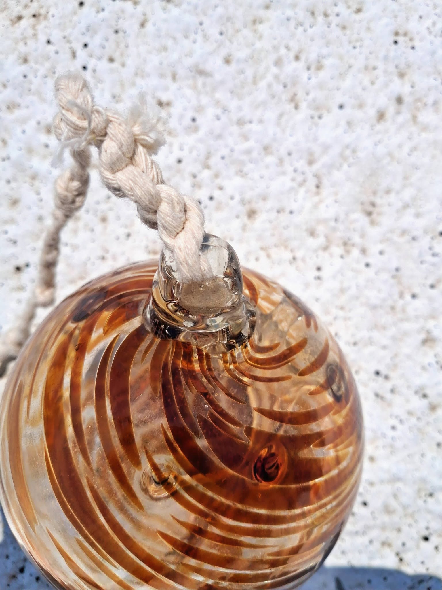 Macro close up of amber swirl witch ball interior showing layered honey and clear glass swirl pattern in sunlight