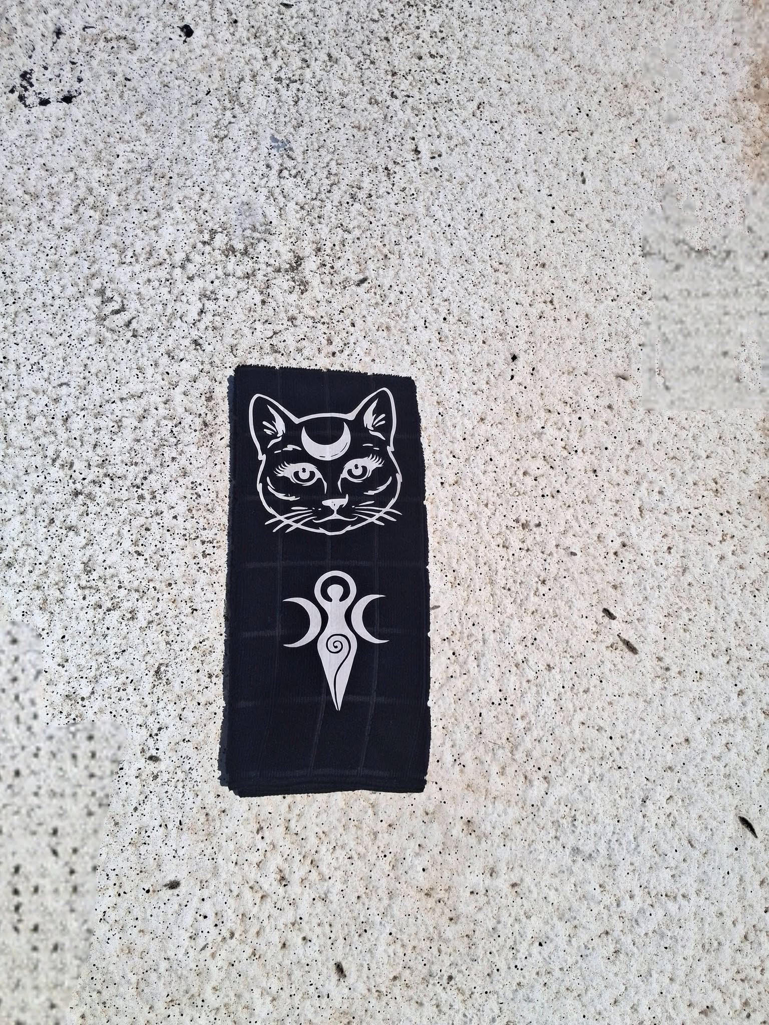 Black microfiber moon cat hand towel rolled view on concrete showing cat face and Triple Moon Goddess symbol detail