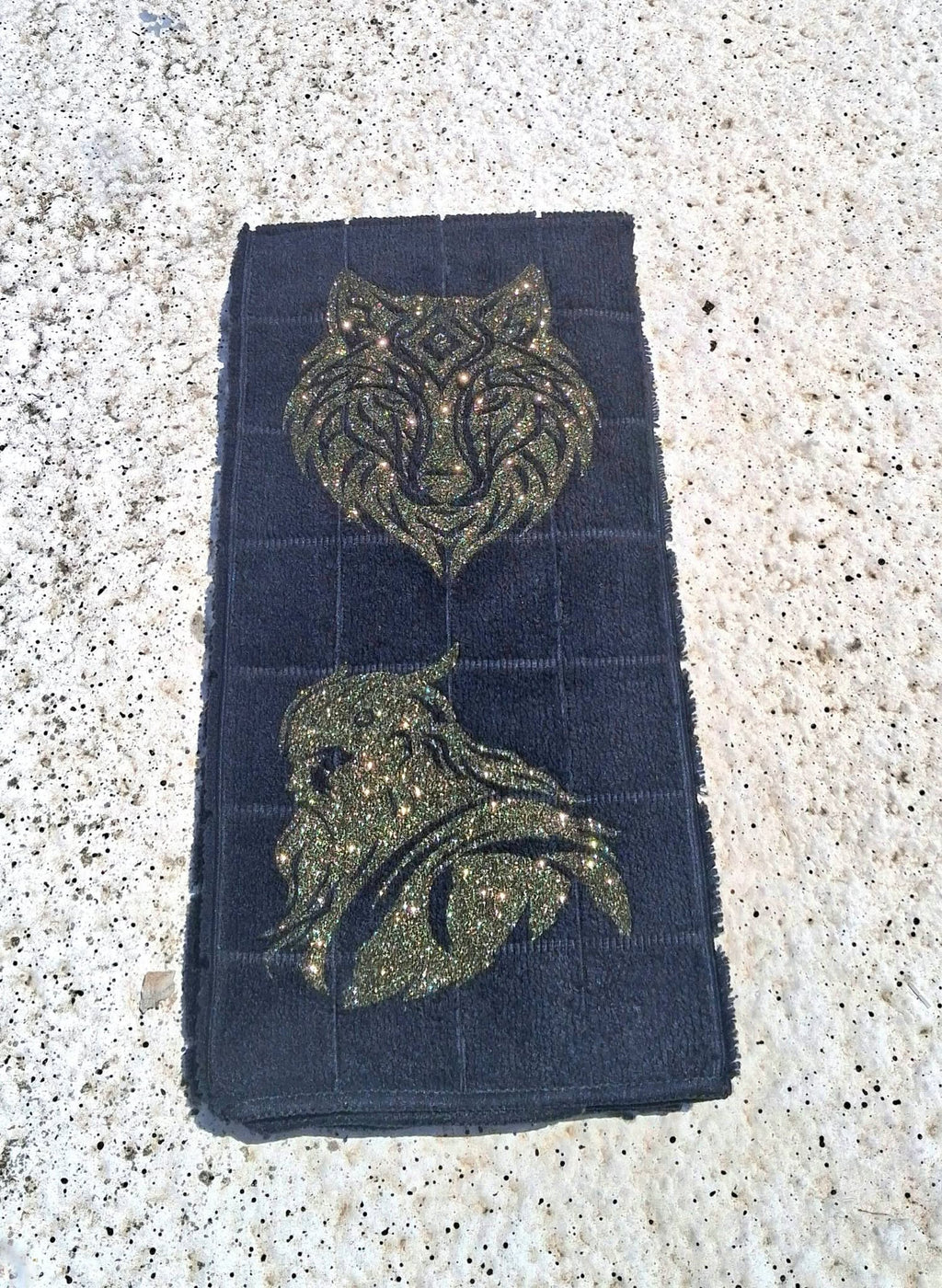 Black microfiber wolf and Viking warrior hand towel second angle on concrete showing both gold glitter designs