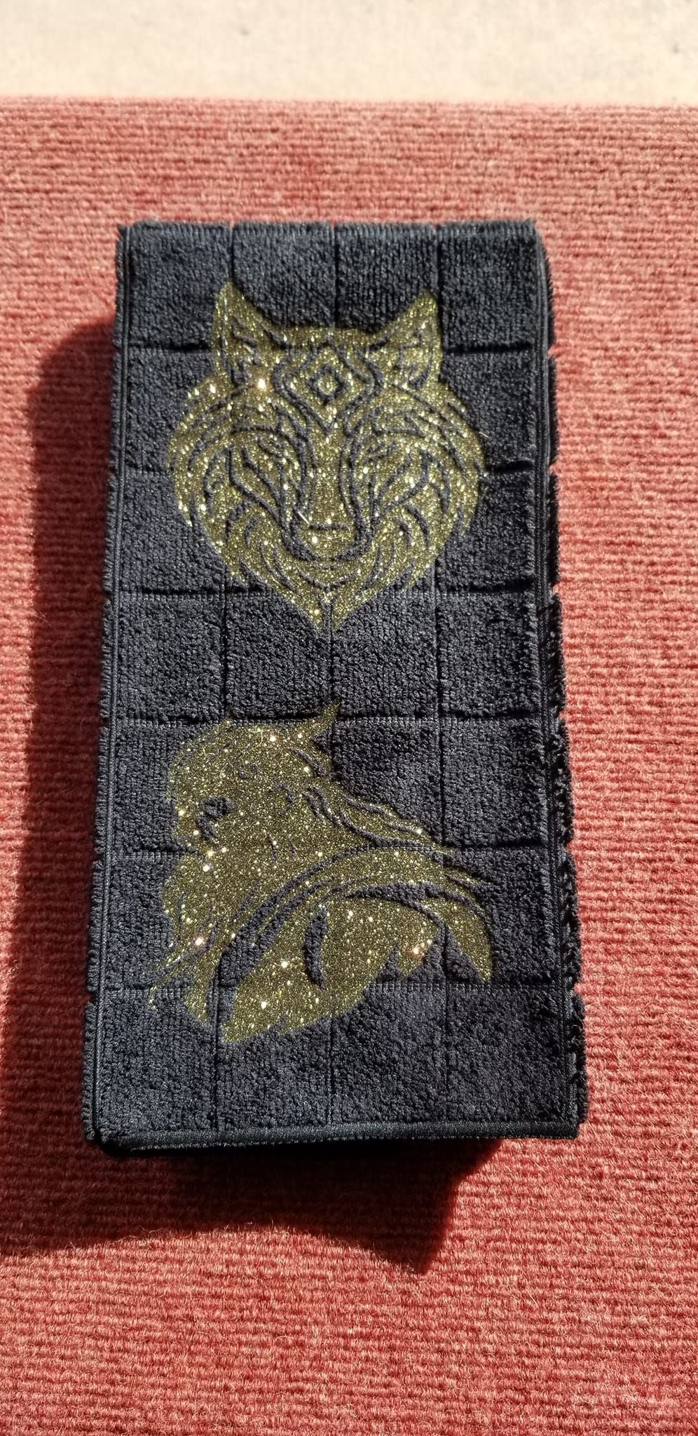 Black microfiber hand towel with gold glitter tribal wolf face and Viking warrior handmade design displayed in store case