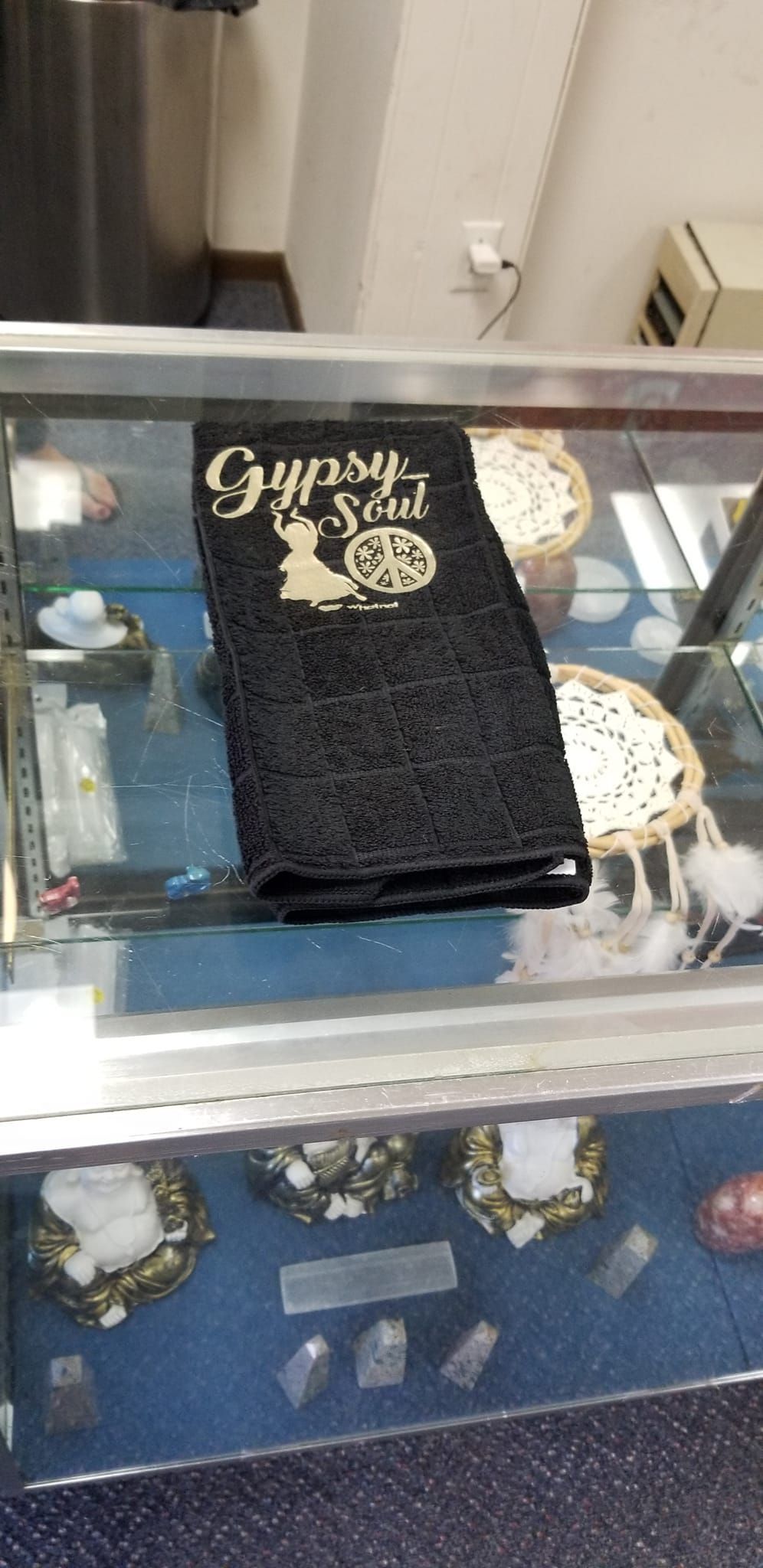 Black microfiber hand towel with white Gypsy Soul cursive script dancing woman silhouette and floral peace sign handmade design displayed in store