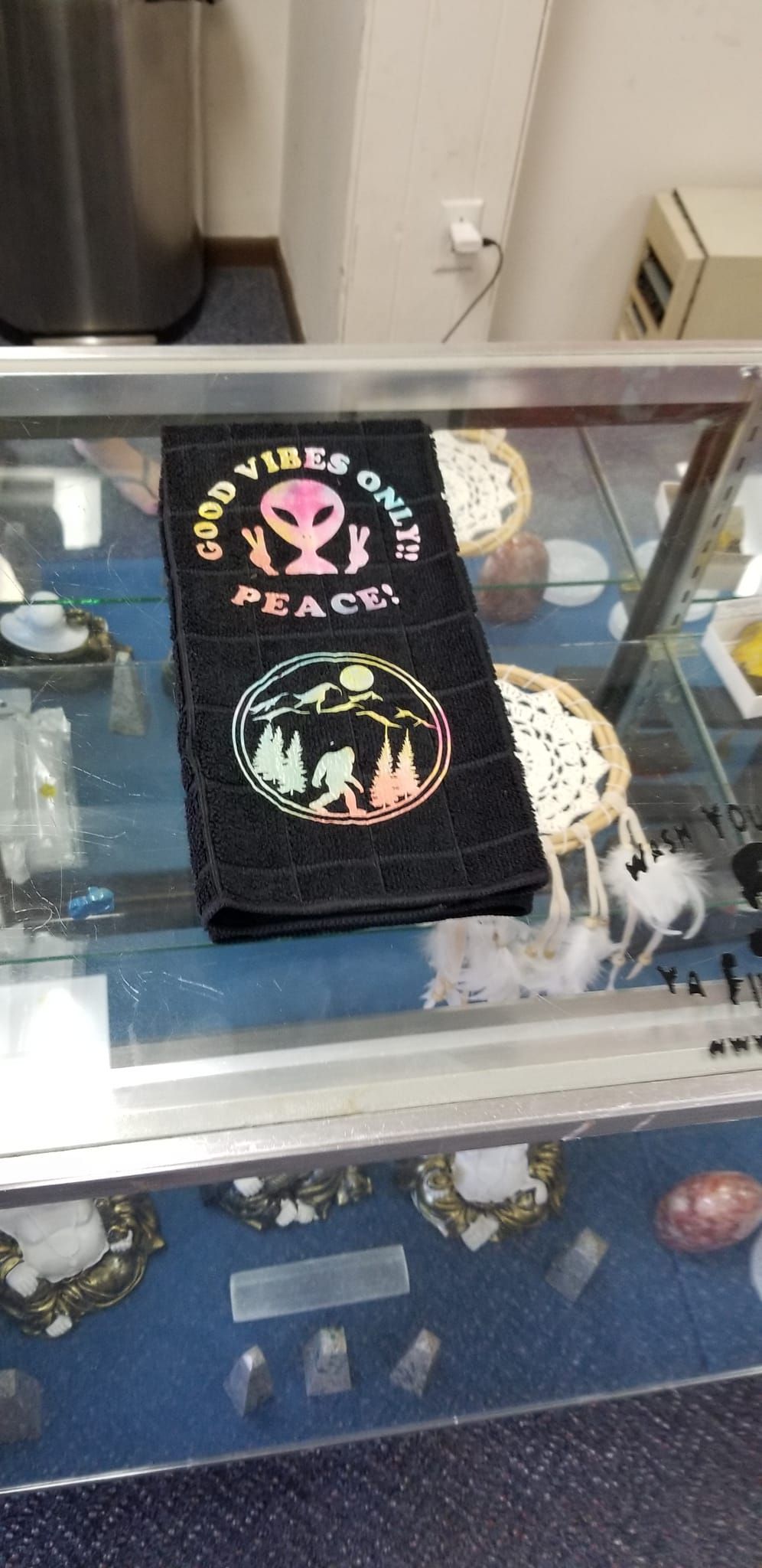 Groovy Bigfoot and Alien Good Vibes Only black hand towel displayed in store
