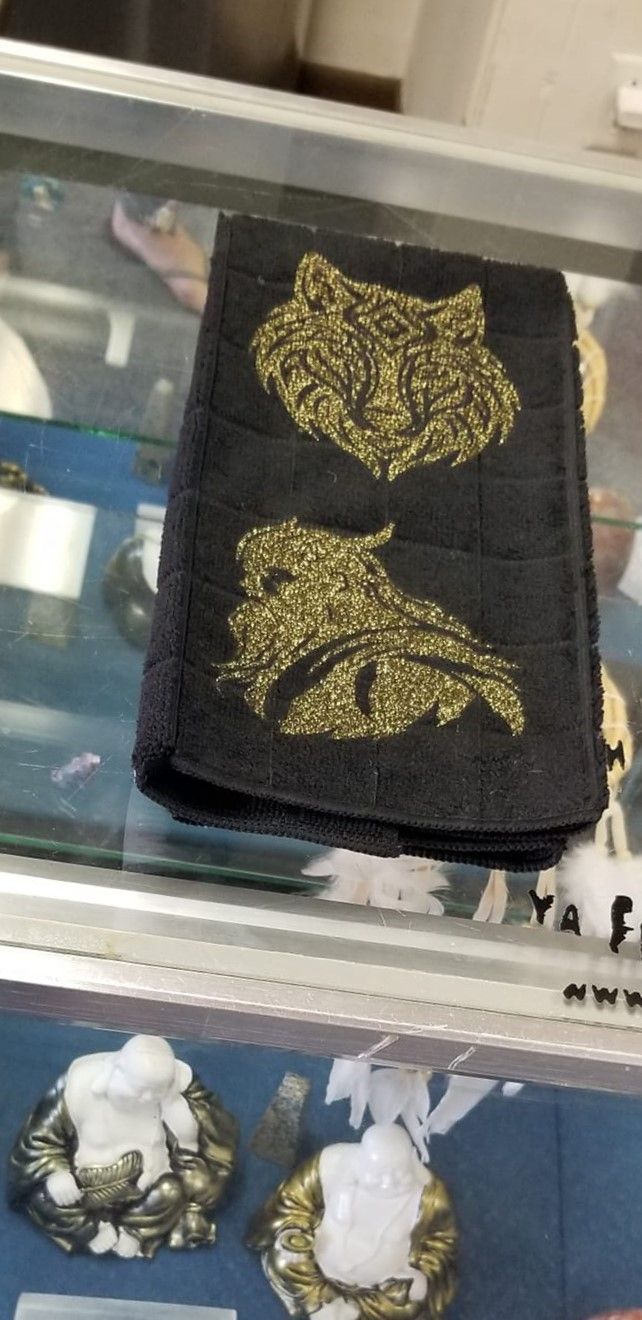 Black microfiber hand towel with gold glitter wolf and Viking warrior design laid flat on concrete full view
