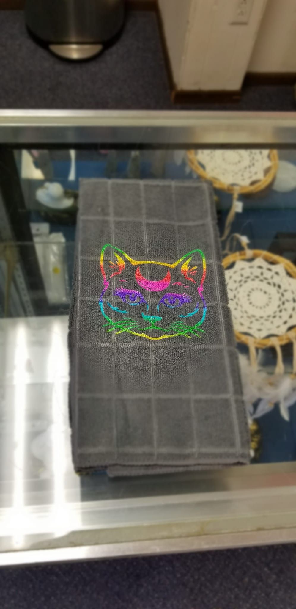 Gray microfiber hand towel with rainbow holographic moon cat crescent moon design handmade by Roosters Peacock displayed in store