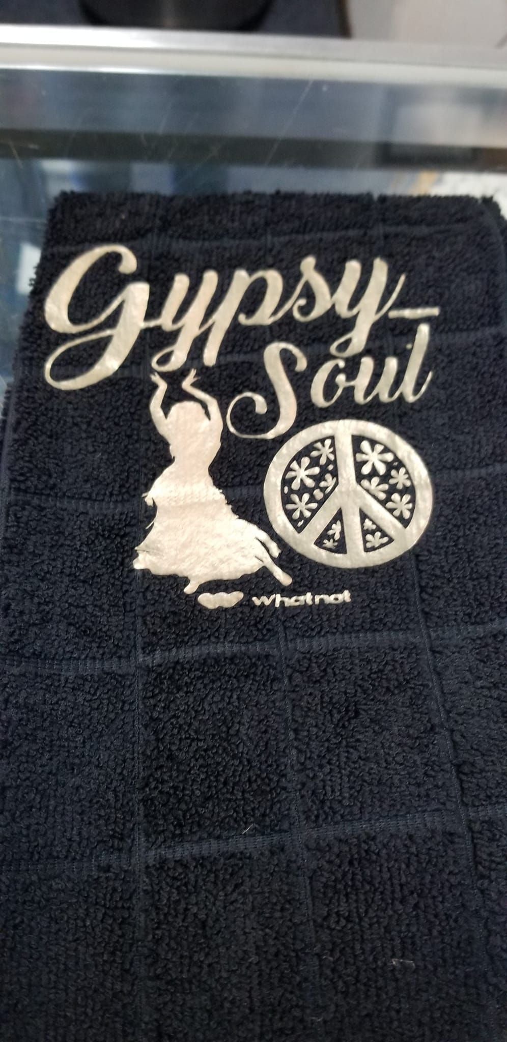 Close up of white Gypsy Soul handmade design on black microfiber towel showing cursive text dancing woman and peace sign detail