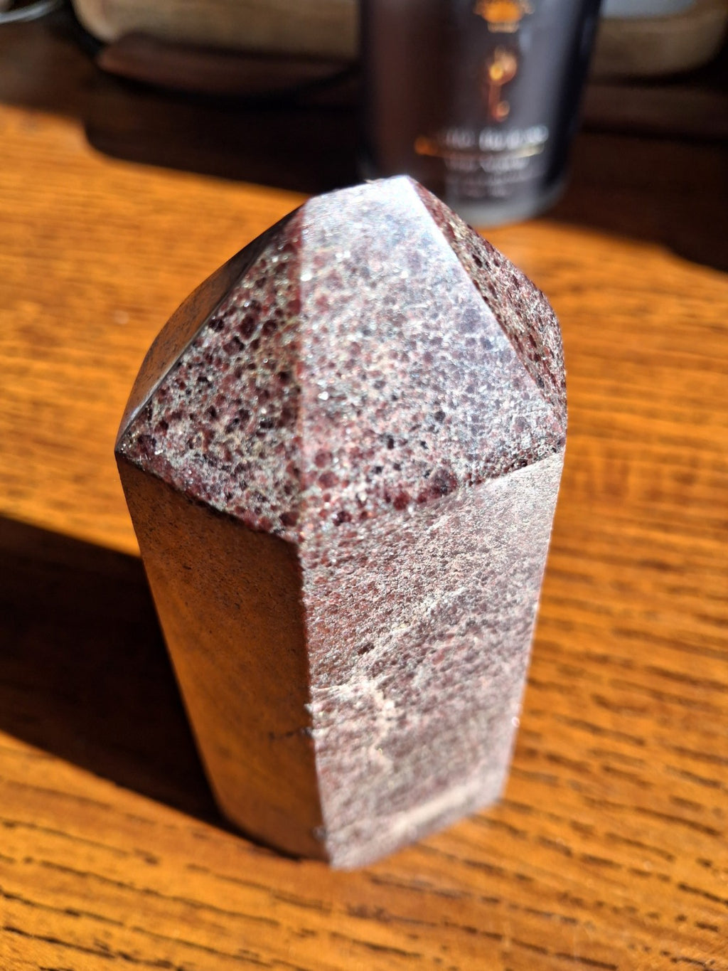 Polished garnet point tower close angle showing flecked burgundy mineral material and pointed tip