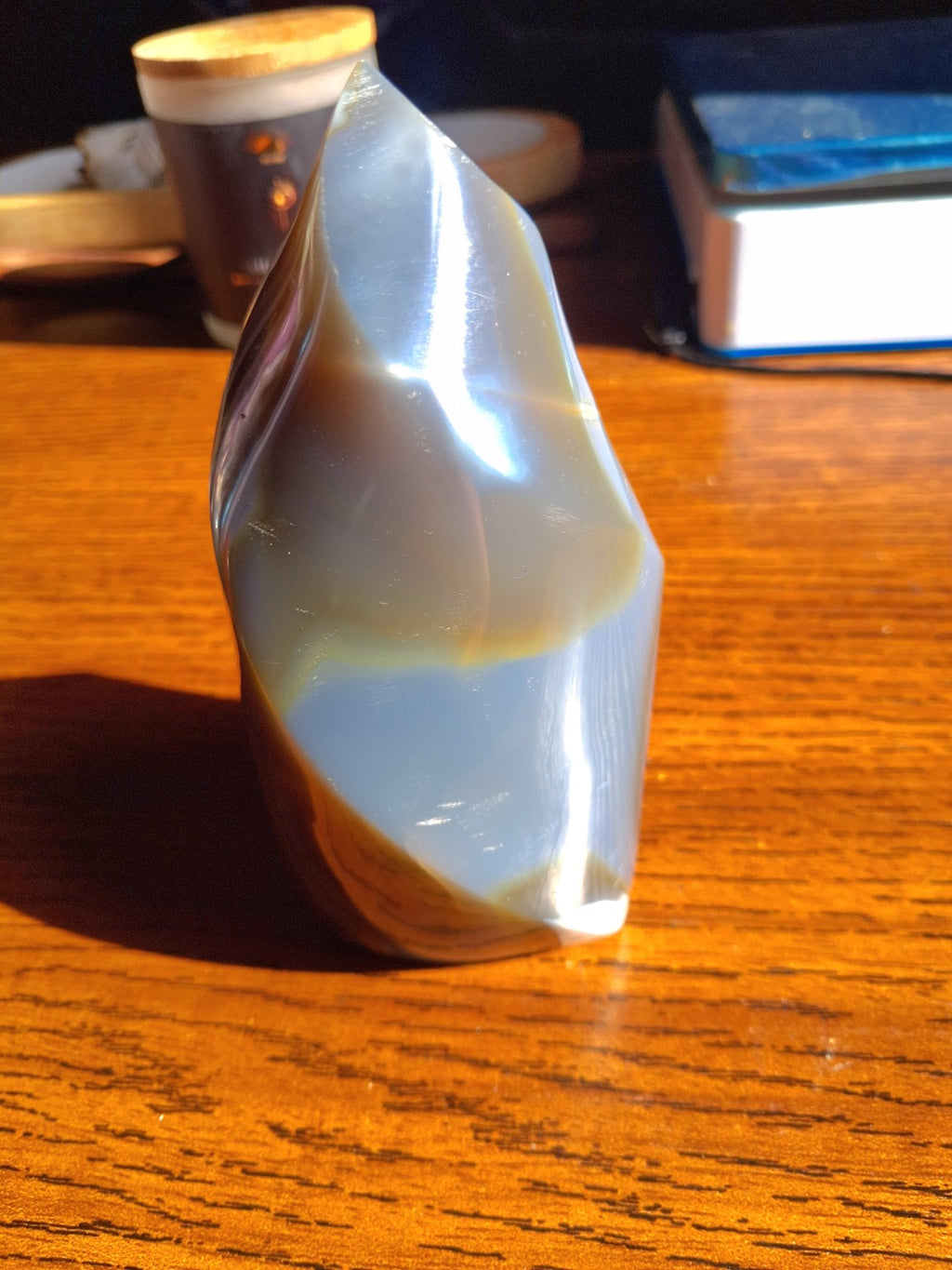 Orca Agate polished 5 inch flame front view on wooden table, gray blue cream and brown bands
