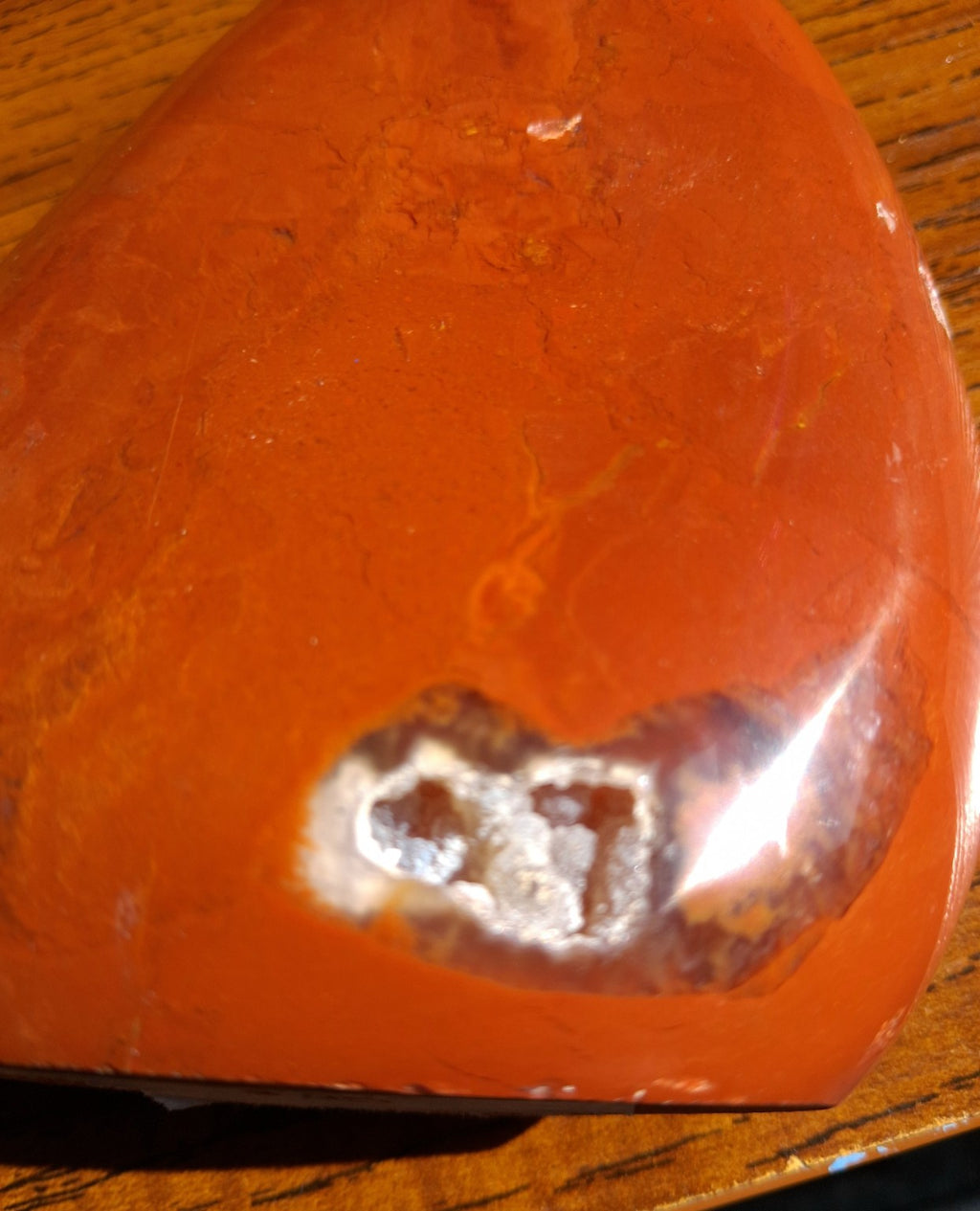 Detailed close-up of natural light-colored mineral pocket on polished Red Jasper freeform