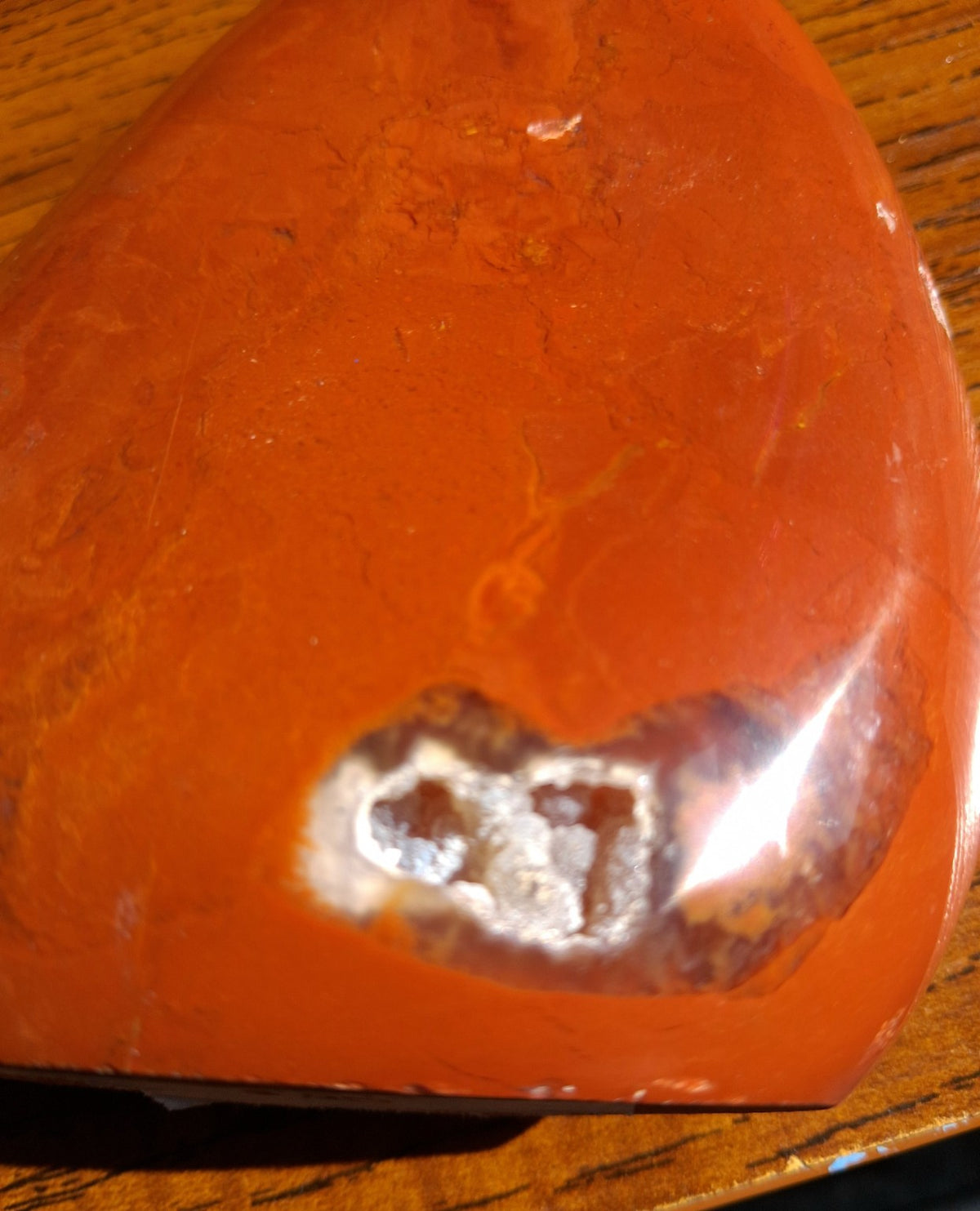 Detailed close-up of natural light-colored mineral pocket on polished Red Jasper freeform
