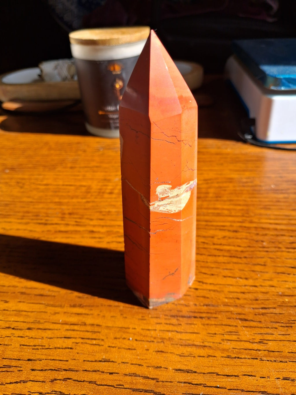 Original straight-on view of tall polished red jasper point showing orange-red faceted sides and cream middle streak